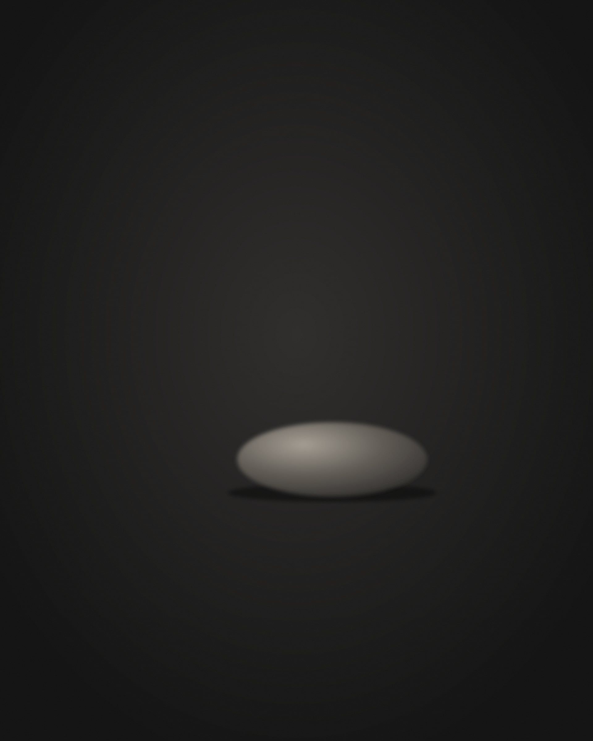 A thin band of light catching one small mark on the object's edge.